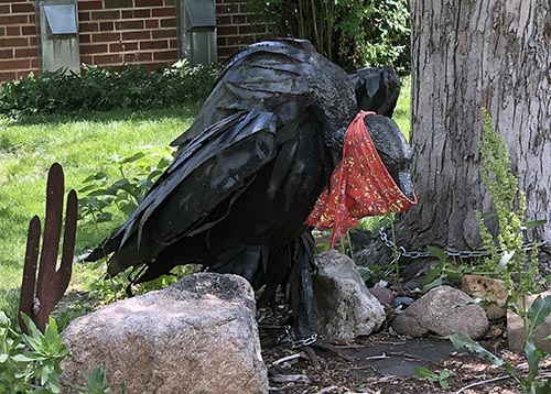 metal vulture statue wearing a quarantine mask
